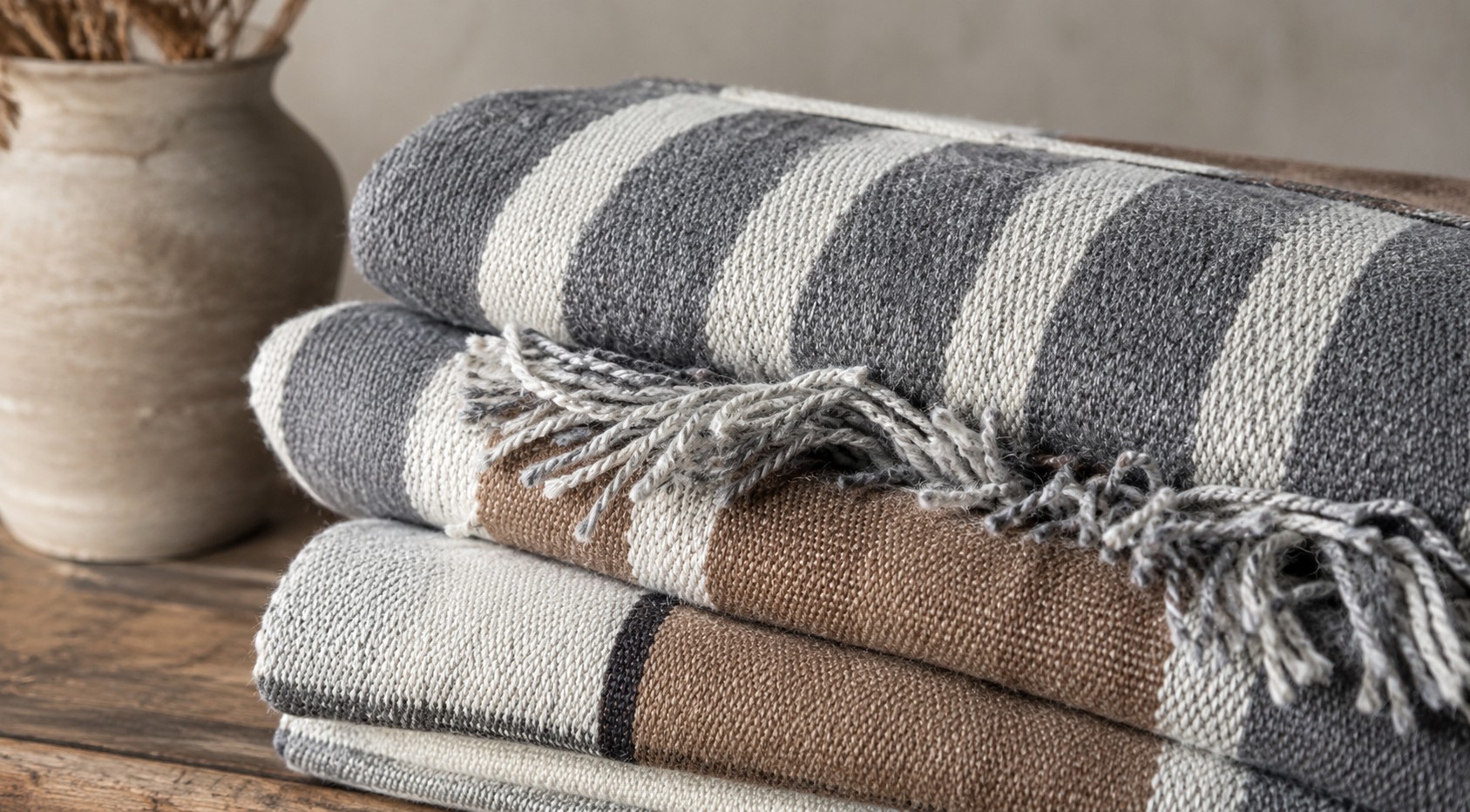 Stack of folded handwoven goat hair rugs in grey, cream and brown stripes